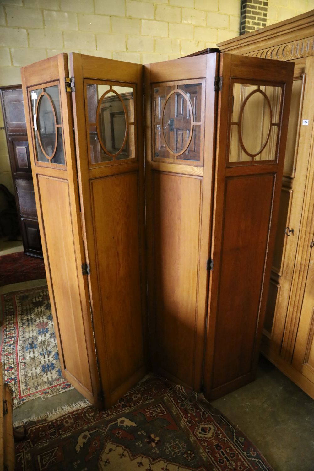 An Edwardian glazed oak four fold dressing screen, each panel 40 x 180cm